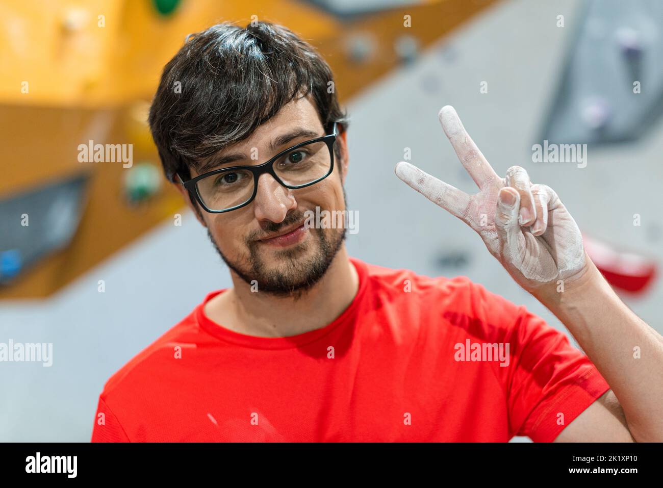 Uomo che fa v gesto con la mano in un sito di arrampicata. Foto Stock