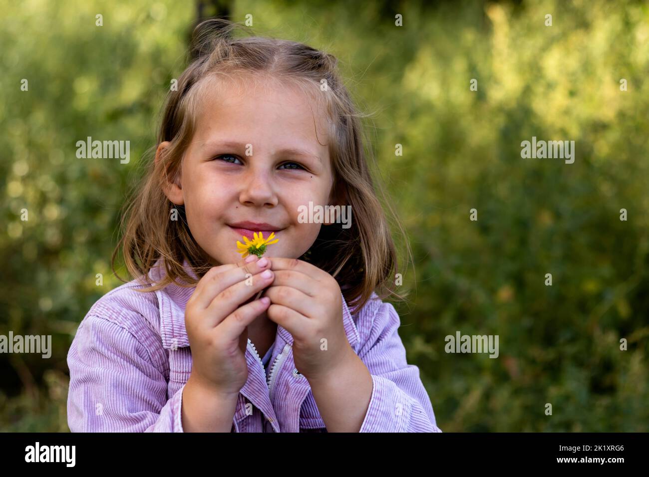 Bambina sorridente nel parco. Spazio di copia. Bambino felice che guarda la macchina fotografica. Ritratto di un ragazzo ridente fuori. Banner. Foto Stock