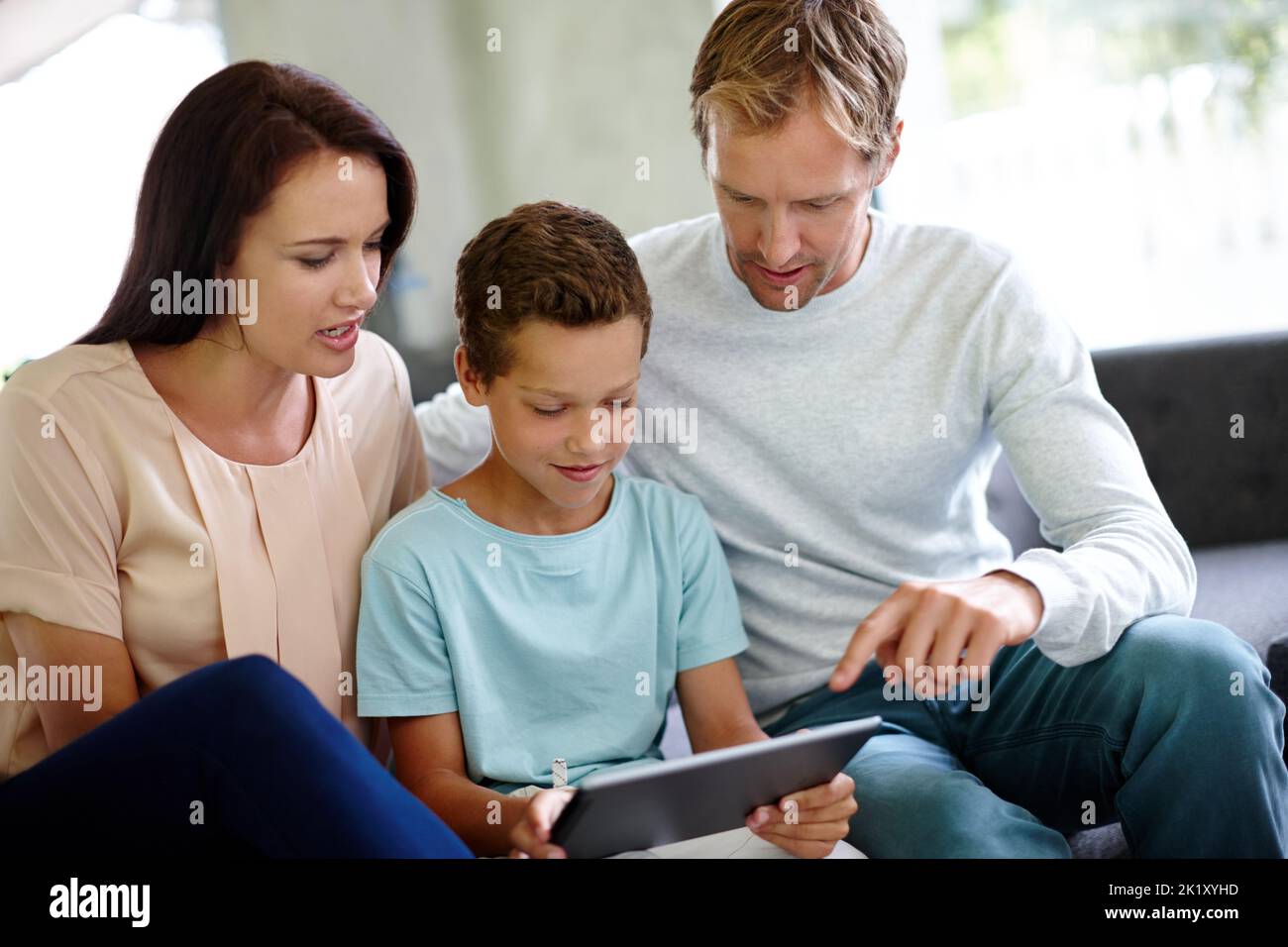 Imparate ogni sorta di cose nuove online. Una famiglia che utilizza un tablet digitale mentre si siede sul divano di casa. Foto Stock
