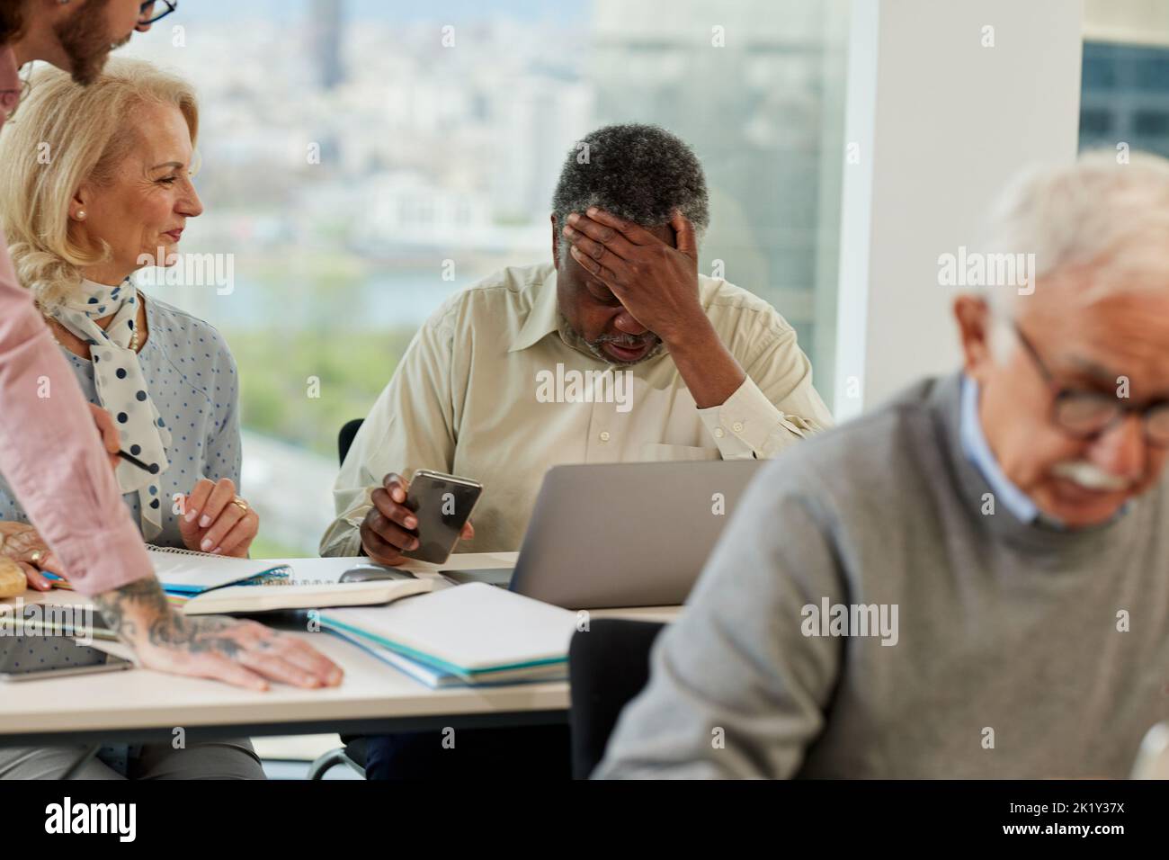 Un uomo africano anziano che ha difficoltà ad imparare l'uso di Internet sul corso per gli anziani in classe. Foto Stock