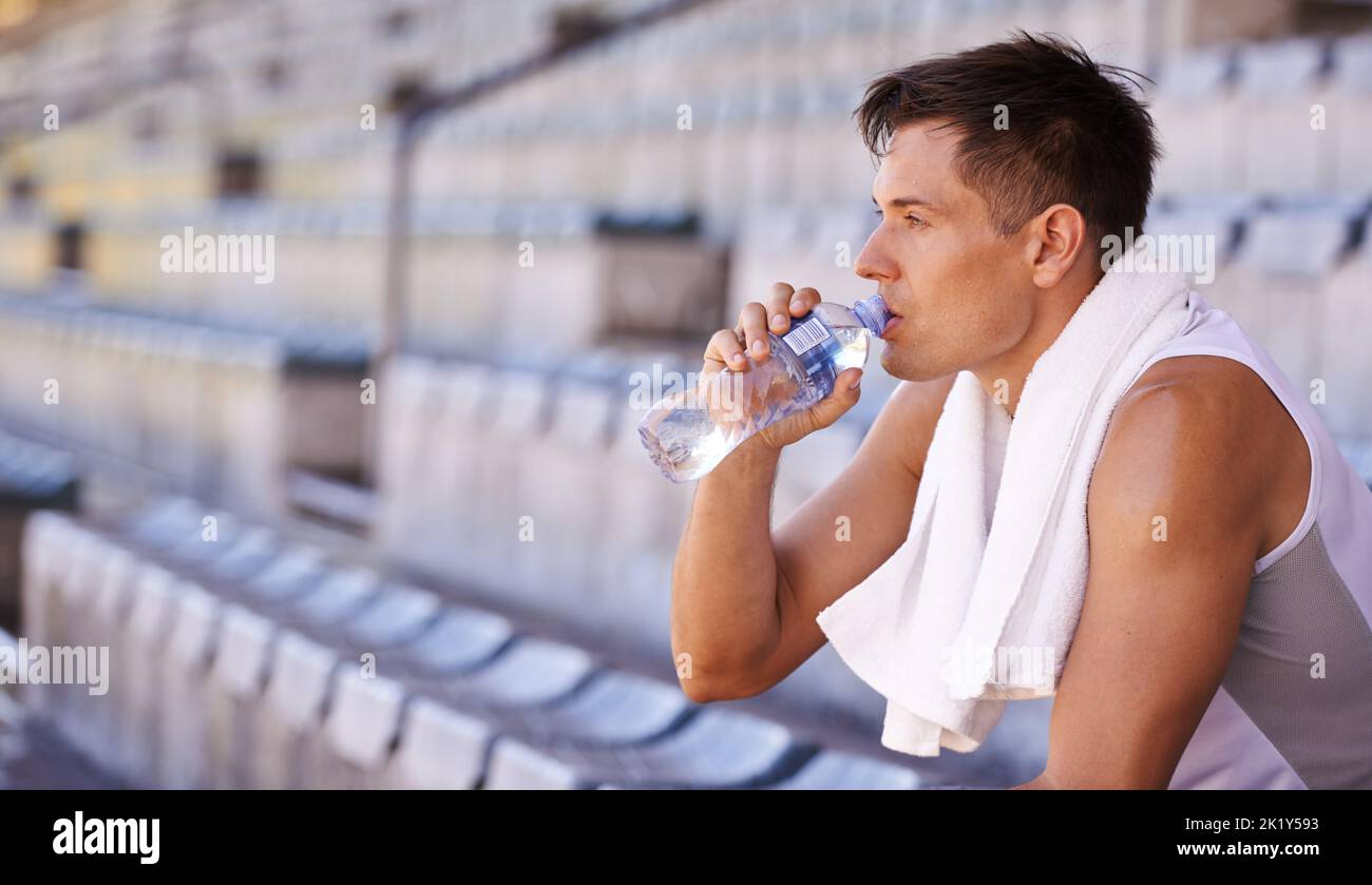 Una pausa rinfrescante. Un atleta che prende una pausa dall'allenamento con un po' d'acqua. Foto Stock