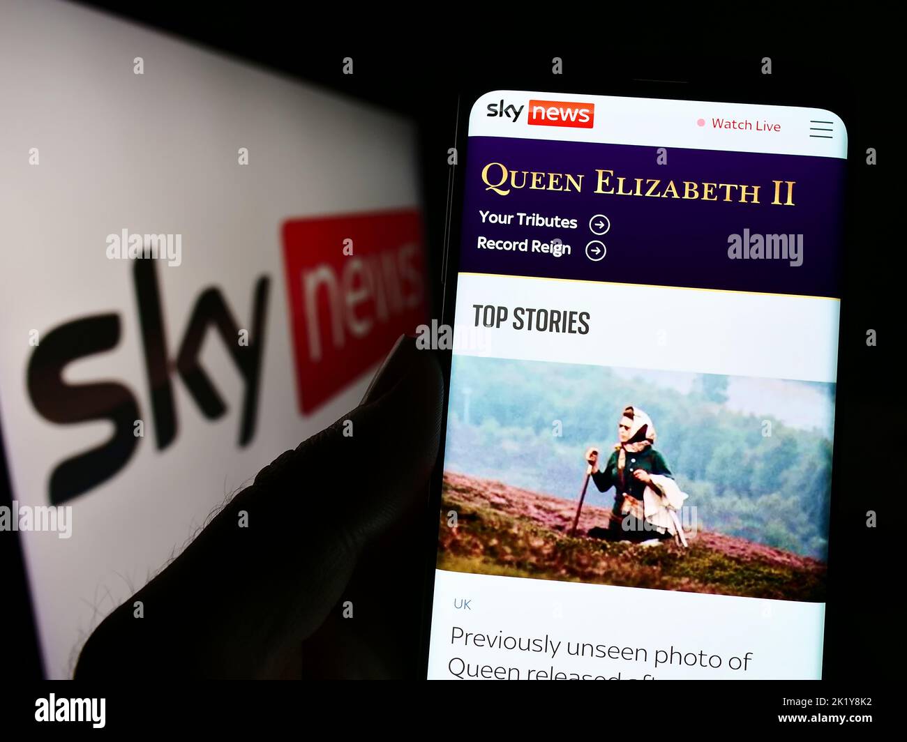 Persona che tiene il cellulare con pagina web del canale televisivo britannico Sky News sullo schermo di fronte al logo. Messa a fuoco al centro del display del telefono. Foto Stock