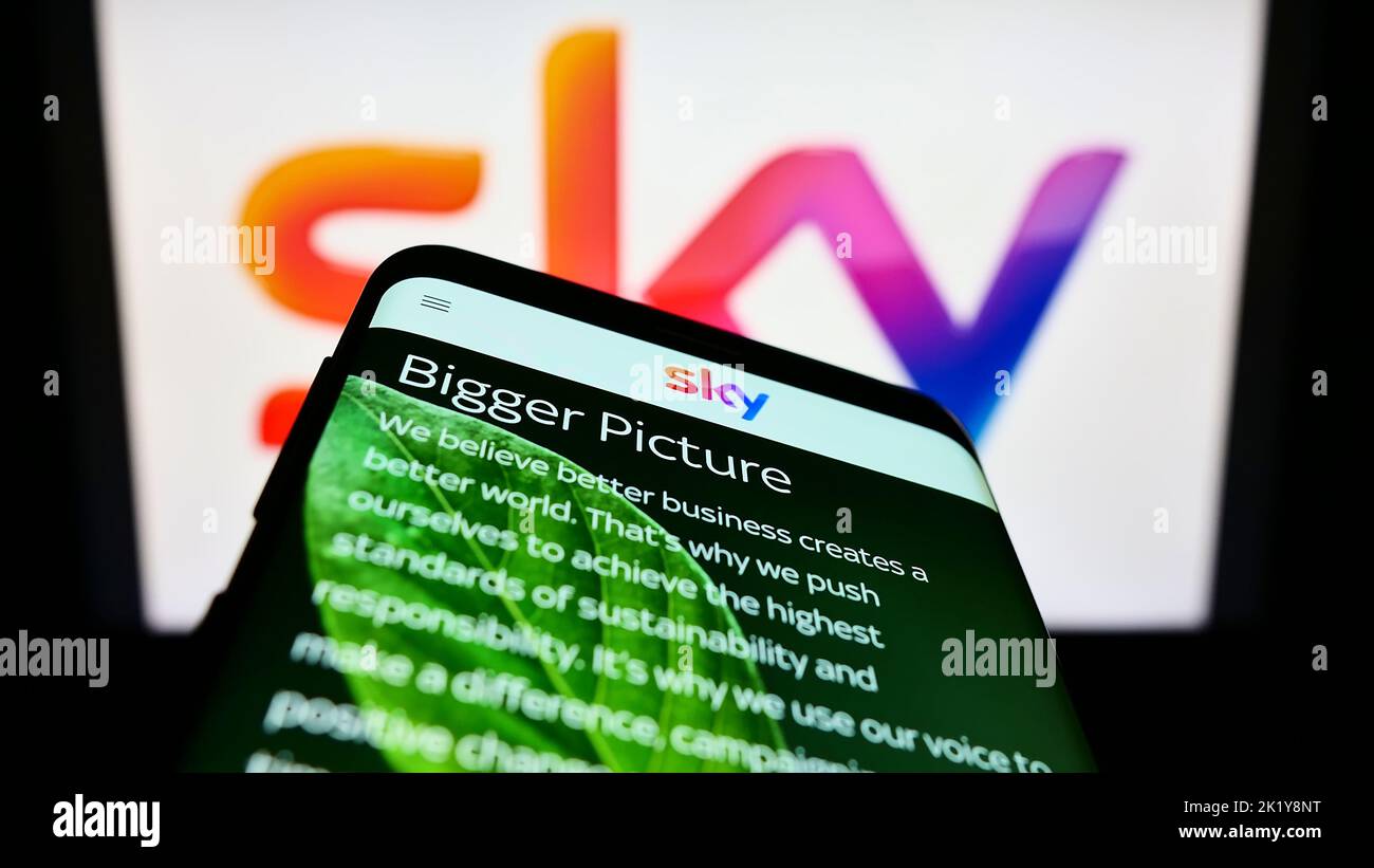Telefono cellulare con pagina web della società di media britannica Sky Group Limited sullo schermo di fronte al logo aziendale. Messa a fuoco in alto a sinistra del display del telefono. Foto Stock