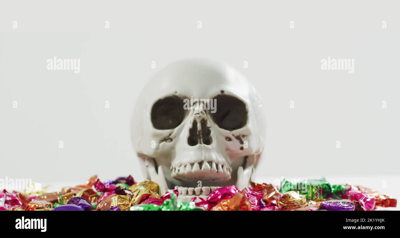 Immagine del testo di Halloween sul cranio con dolci su sfondo grigio Foto Stock