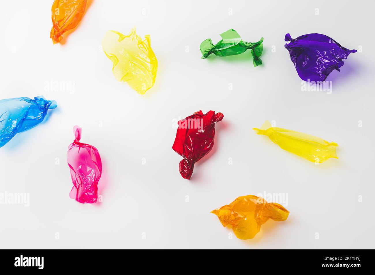 Coloratissimi involucri di caramelle su bianco. Concetto di dolci allo zucchero. Sfondo colorato astratto Foto Stock