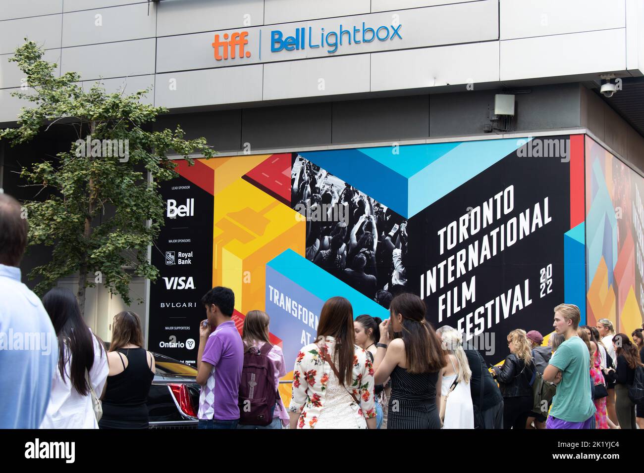 Una folla fuori dall'ingresso principale delle celebrità al TIFF, il Toronto International Film Festival, accanto a un poster colorato sullo sfondo. Foto Stock