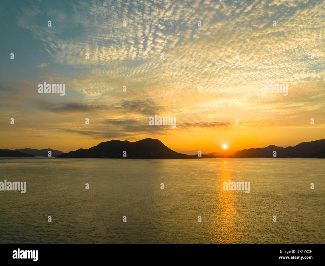 Il sole mattutino si trova in basso sul paesaggio costiero Foto Stock