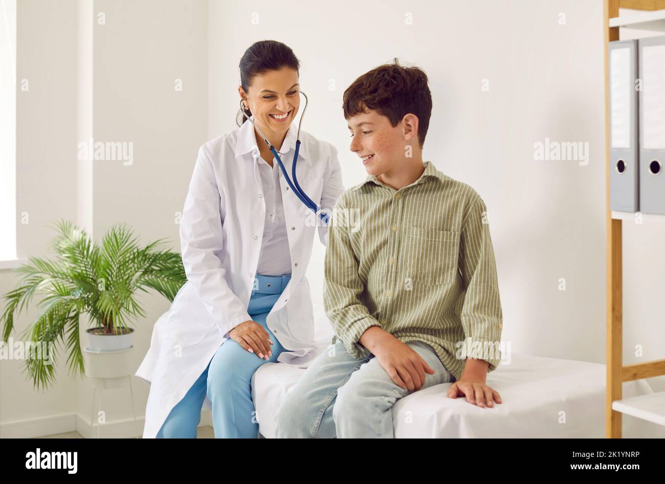 Bambino piccolo felice ottenere un controllo del cuore o dei polmoni all'ufficio del pediatra Foto Stock