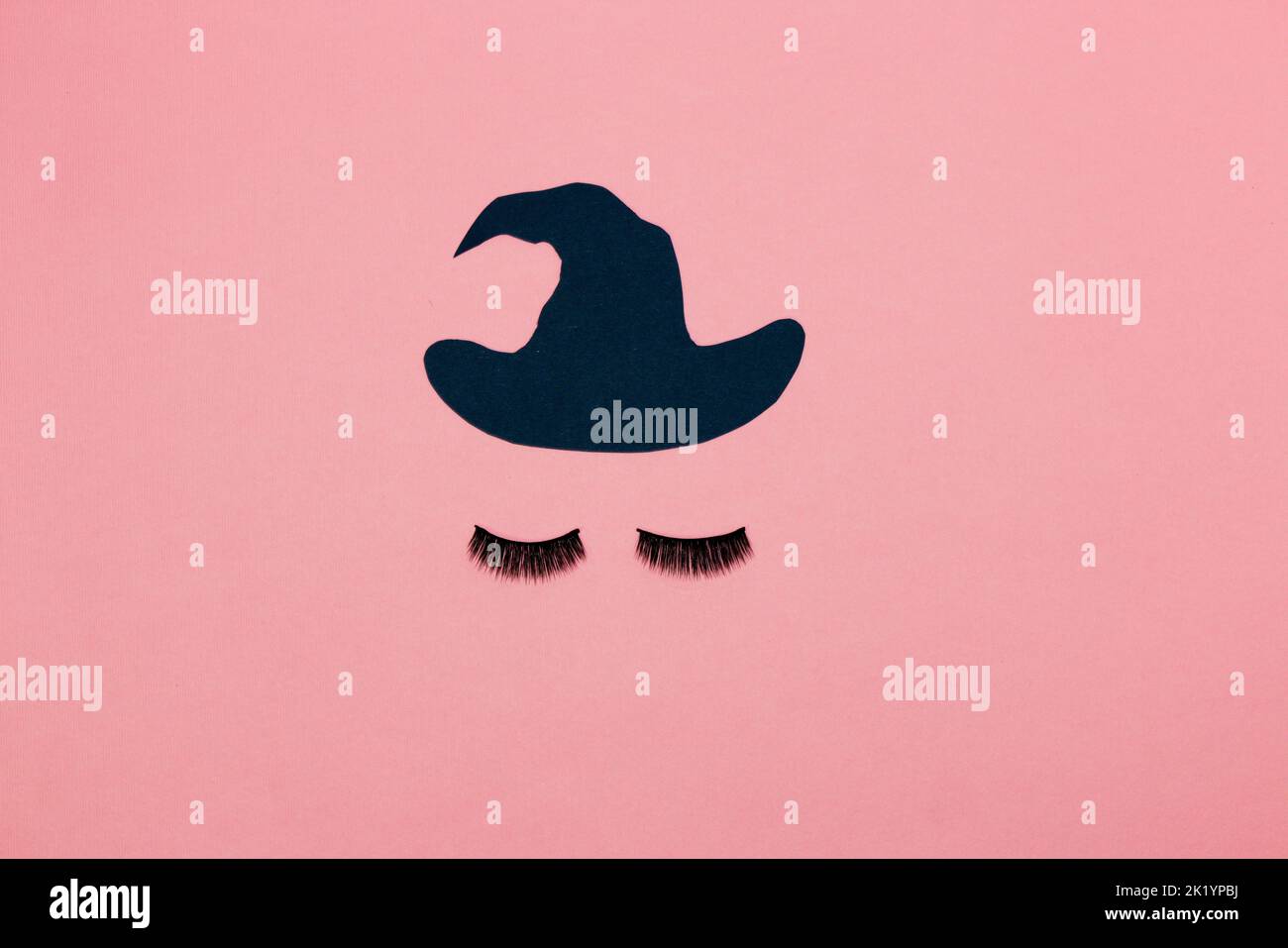 strega della signora, ciglia e cappello su fondo rosa, disegno creativo di arte, concetto di halloween, posa piatta Foto Stock