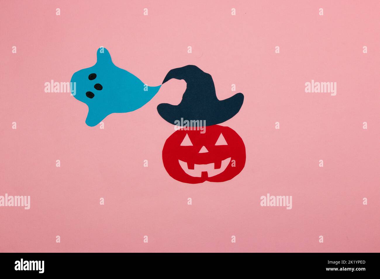 zucca di carta rossa con un cappello blu da cui esce il fantasma, concetto creativo di halloween, posa piatta, carta artigianale Foto Stock