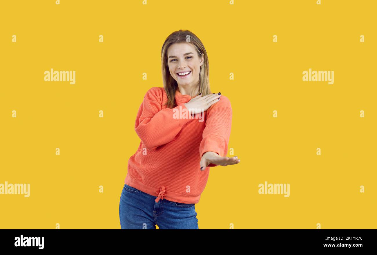 Ritratto di felice bella giovane donna sorridente e danzante isolato su sfondo giallo Foto Stock