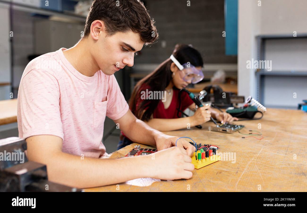 Diversi giovani studenti delle scuole superiori che imparano nella classe elettronica di robotica scientifica Foto Stock