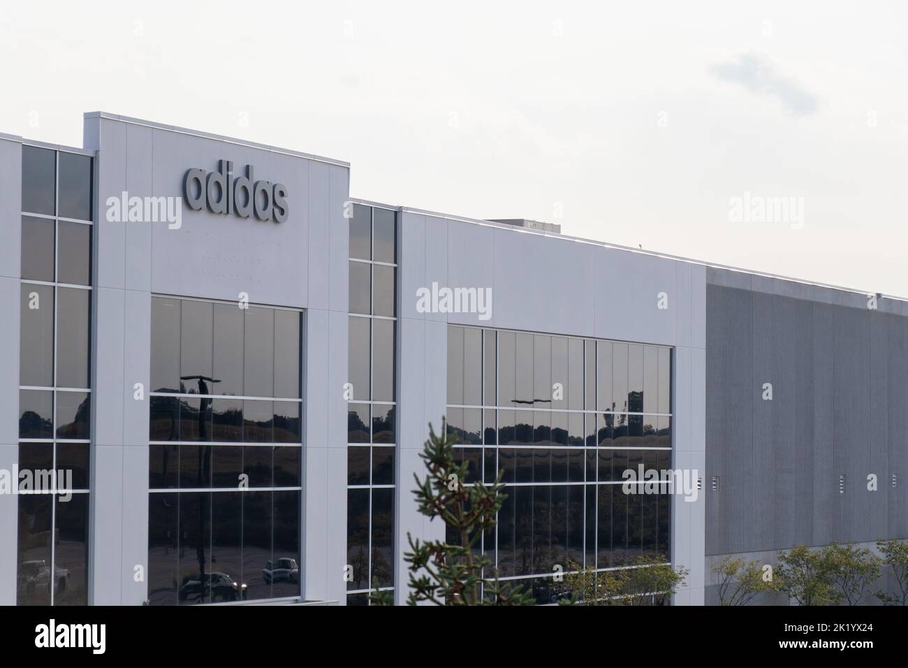 Il logo Adidas è visto in cima a un ufficio Adidas e magazzino in una giornata nuvolosa. Foto Stock