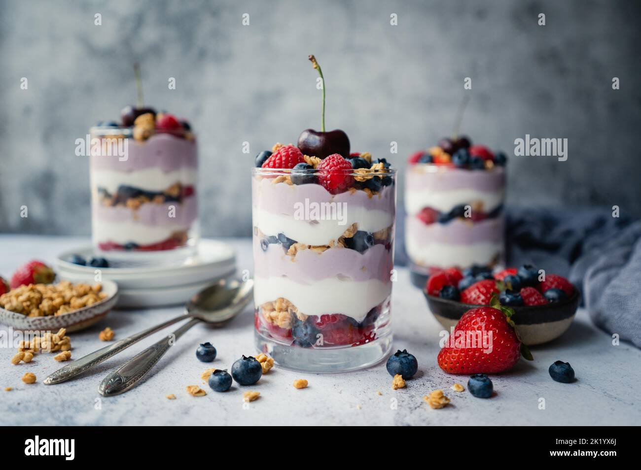Primo piano di parfait misti di yogurt bacca su sfondo grigio. Foto Stock