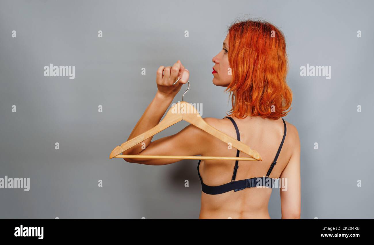 Donna snella dai capelli rossi con appendiabiti vuoto. Vista posteriore. Pubblicità vendite Black Friday. Shop concept, vendita, gancio vuoto. Foto Stock