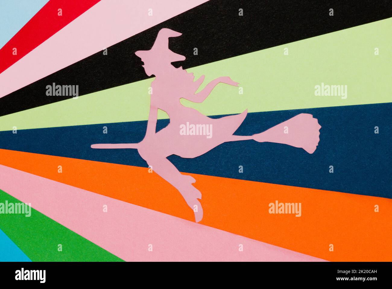 silhouette rosa di una strega che vola su una scopa su un colorato sfondo artistico, creativo concetto di halloween, piatto, carta artigianale Foto Stock