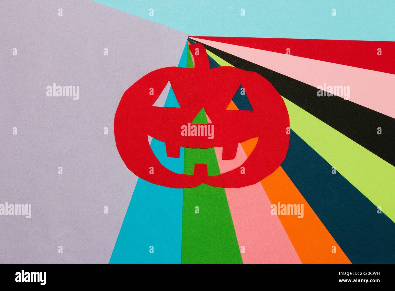 zucca rossa intagliata su sfondo colorato, arte creativa halloween concetto, piatto, carta artigianale Foto Stock