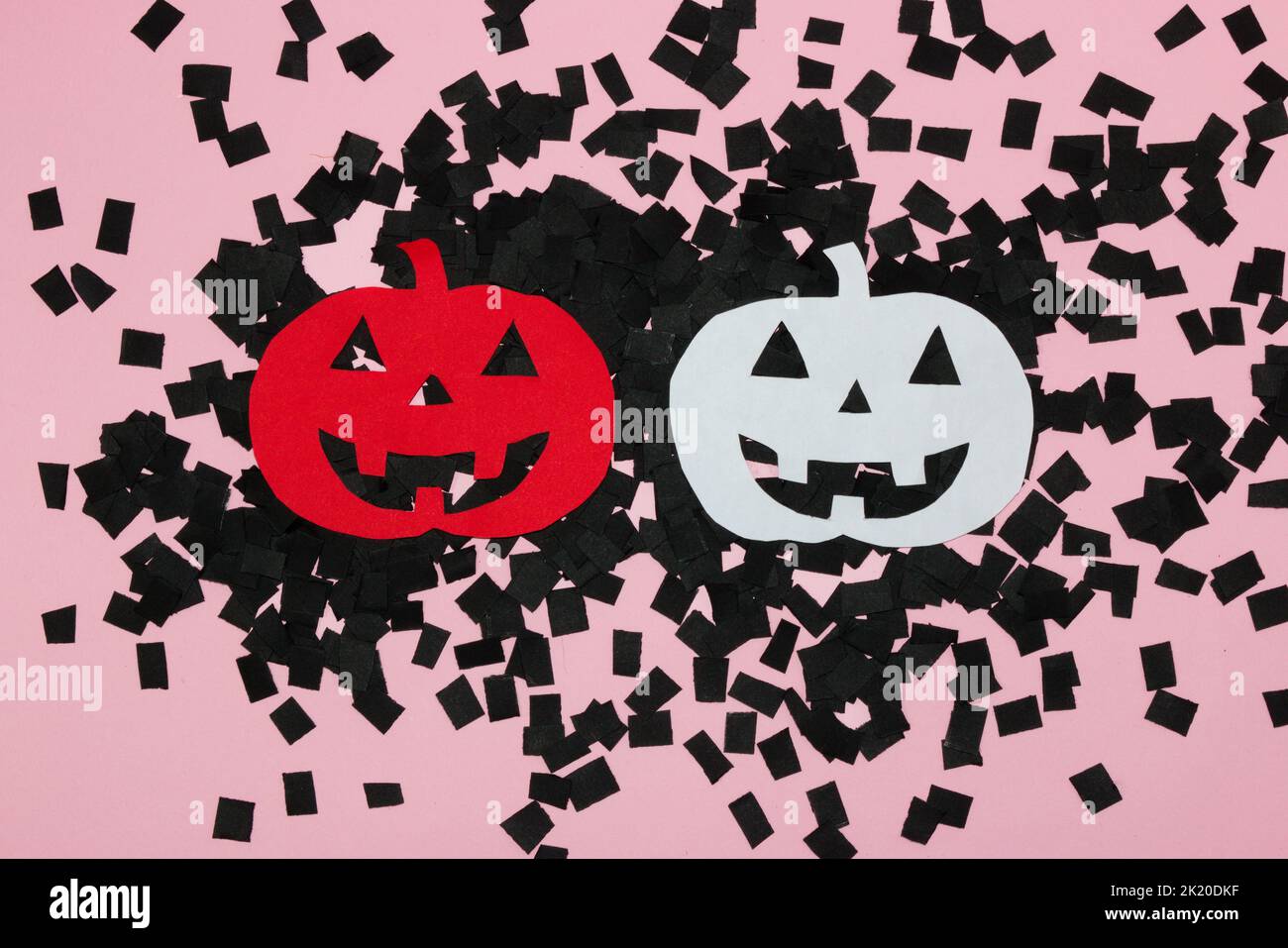 Carta rossa e bianca zucca di Halloween su sfondo rosa ricoperta di carte nere tagliate, design creativo, posa piatta, carta artigianale Foto Stock