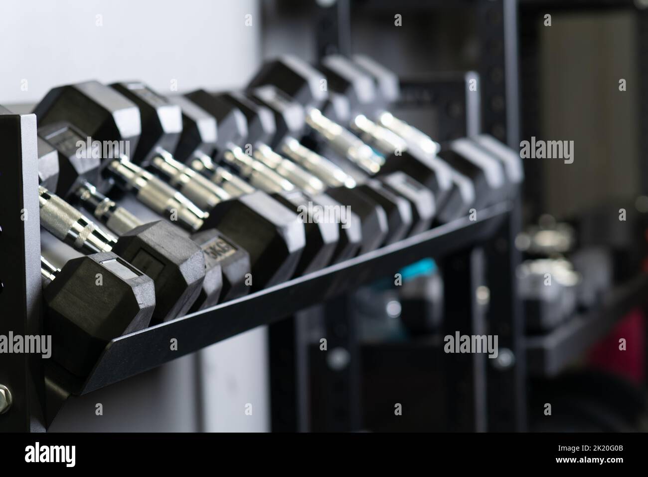 Dumbbell parete blurry palestra casa set attrezzatura di stoccaggio, da studio prendendo in pesante e uomo forte, potenza difficile. , Foto Stock