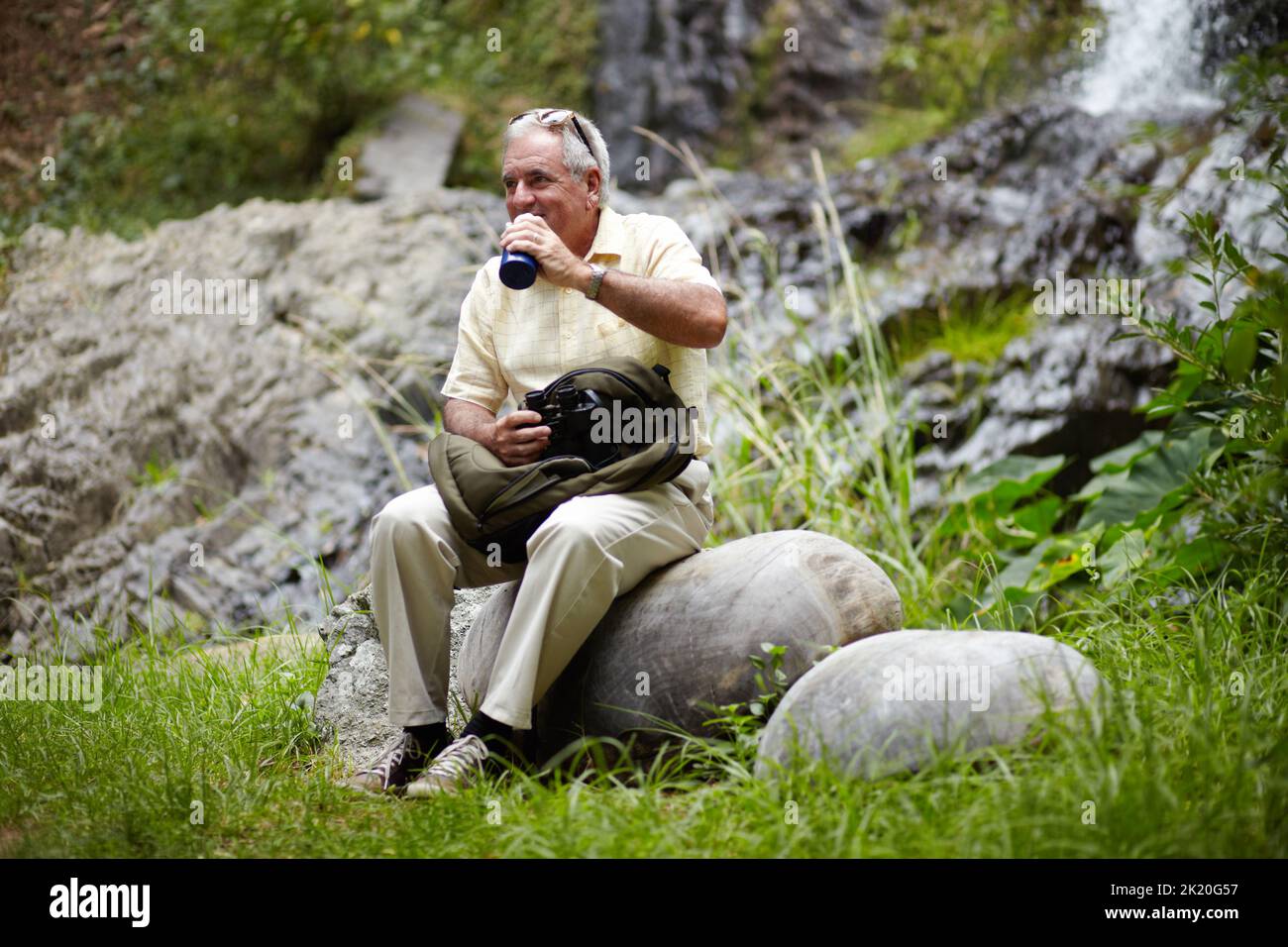 Niente come una passeggiata nella natura... un uomo anziano che ha una pausa in acqua mentre fuori esplorando la natura. Foto Stock