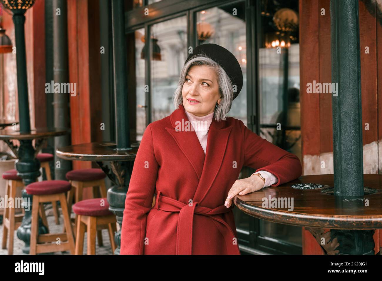 Donna anziana che cammina al tavolo del caffè nel ristorante. Vecchia signora anziana in pensione a piedi sulla strada della città. Elegante anziano pensionato. Abbastanza Foto Stock