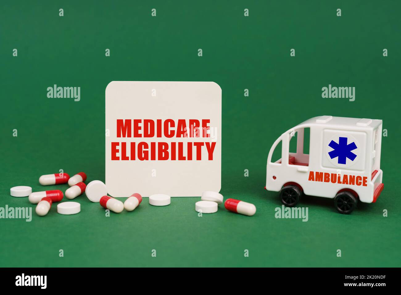 Concetto medico. Su una superficie verde, un'ambulanza, pillole e un segno con l'iscrizione - Medicare eleggibilità Foto Stock