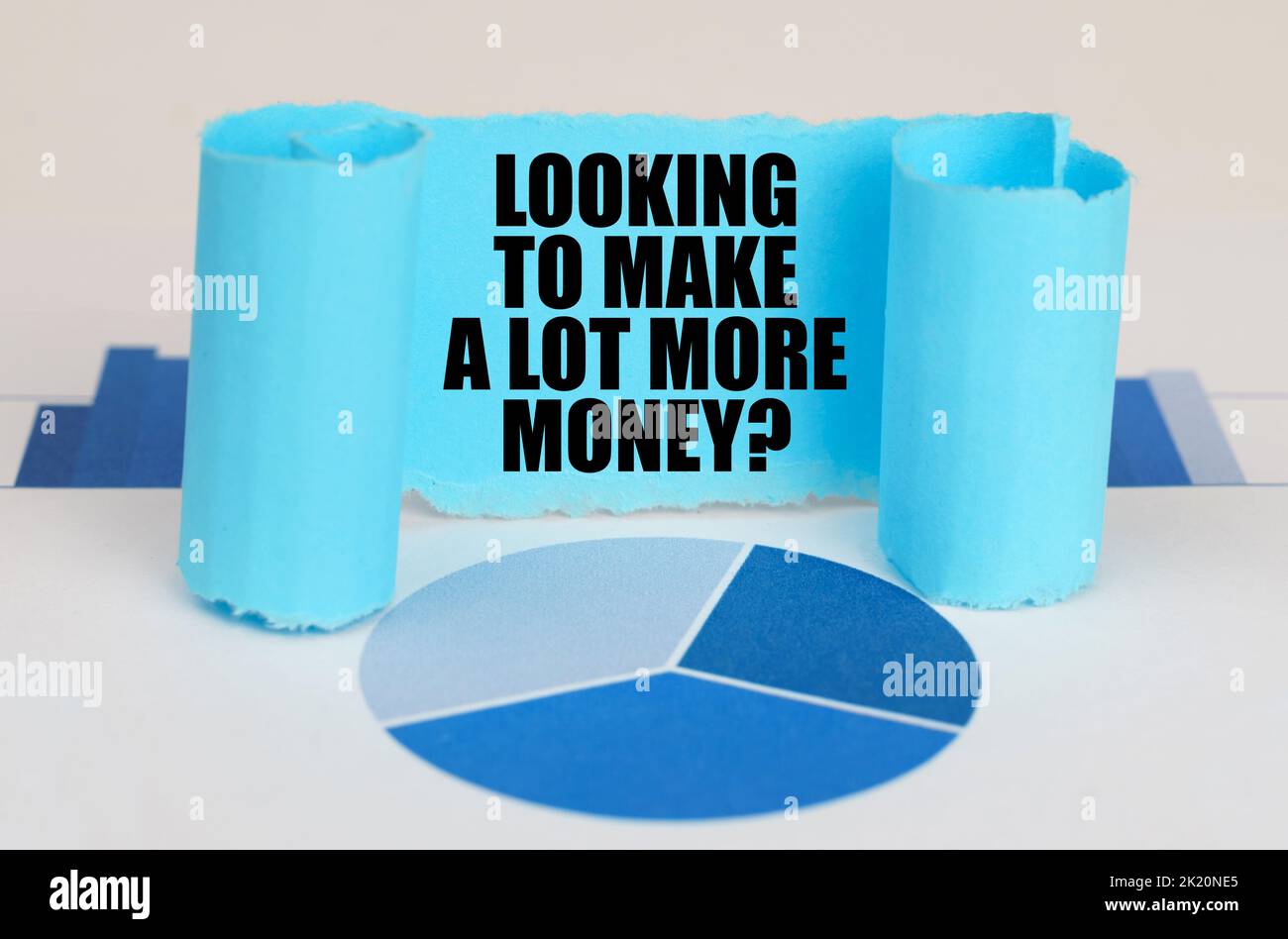Concetto aziendale. Sul diagramma e sui grafici blu c'è una piastra di carta ritorta con l'iscrizione - cercando di fare molto più soldi Foto Stock