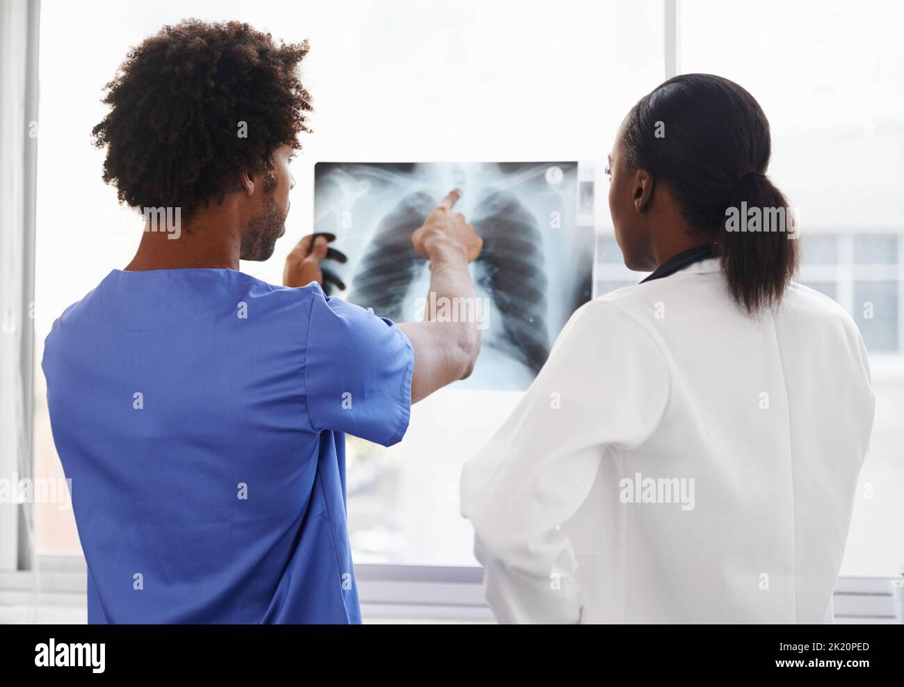 Segnalare anomalie ai raggi X. medico e infermiere di sesso femminile che studiano i raggi X. Foto Stock