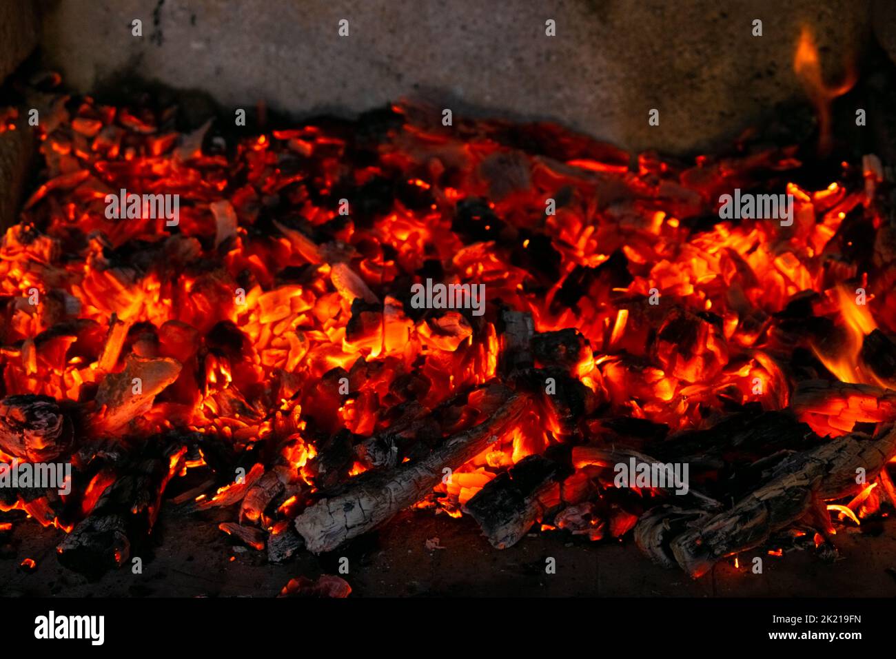Carboni brucianti nel fuoco. Le brace di legno bruciano con fuoco rosso ad alta temperatura Foto Stock