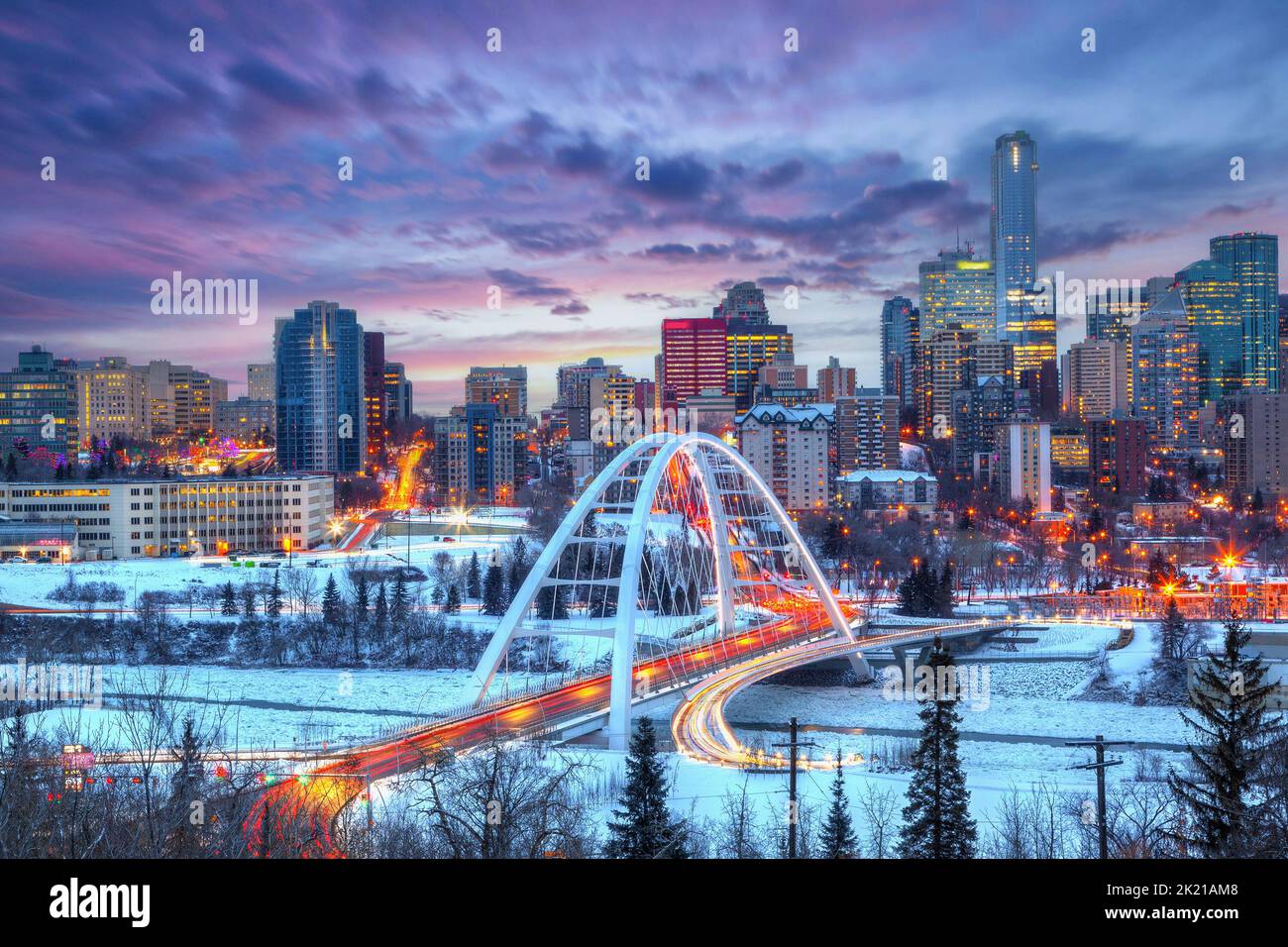 Sentieri leggeri dal semaforo delle ore di punta fino al centro di Edmonton skyline tramonto invernale che mostra il ponte Walterdale attraverso il Saskatc ghiacciato e innevato Foto Stock