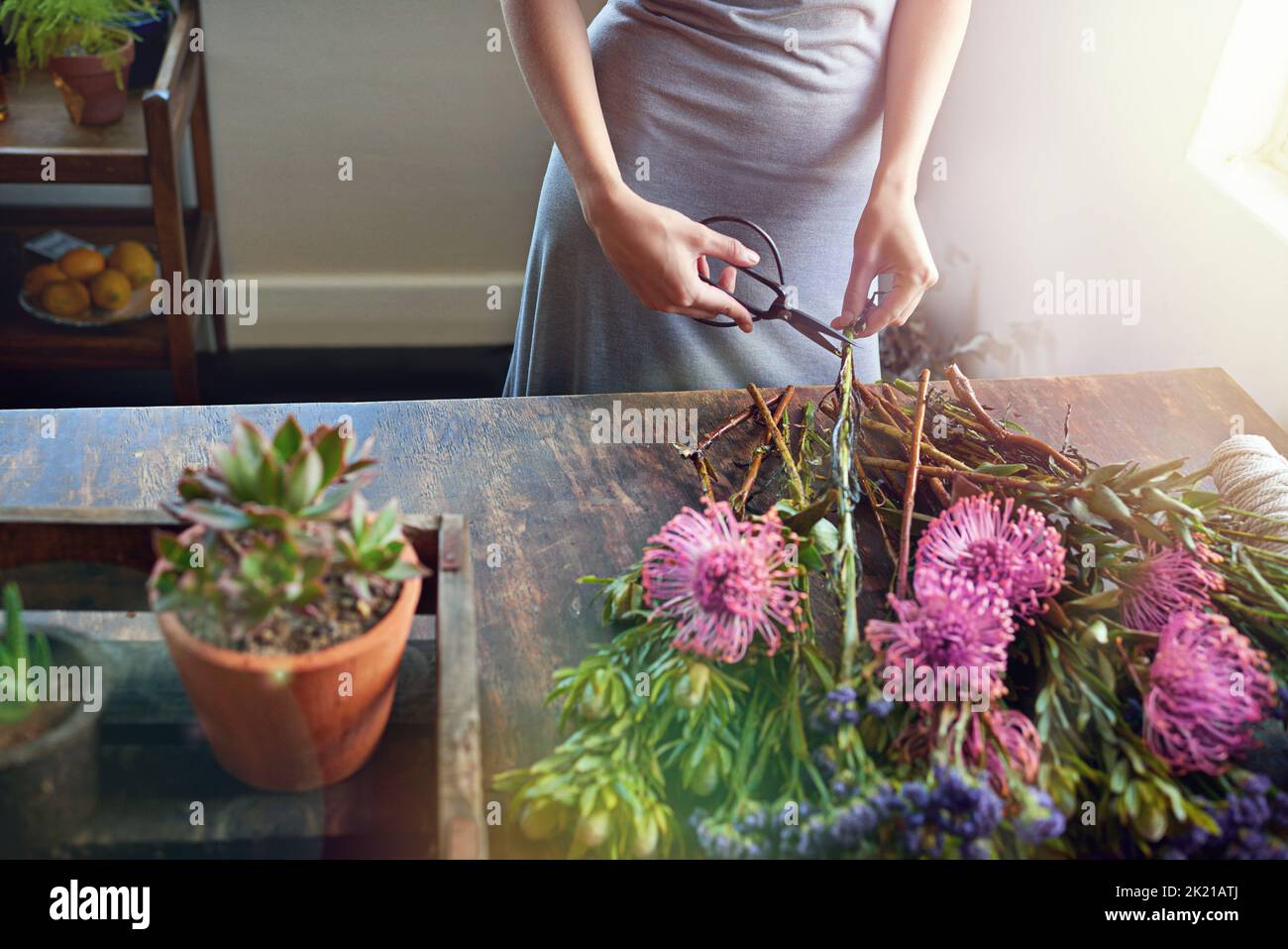 Lascia ottenere creativo. Un bouquet floreale grazioso che è completato su un piano del contatore di legno. Foto Stock