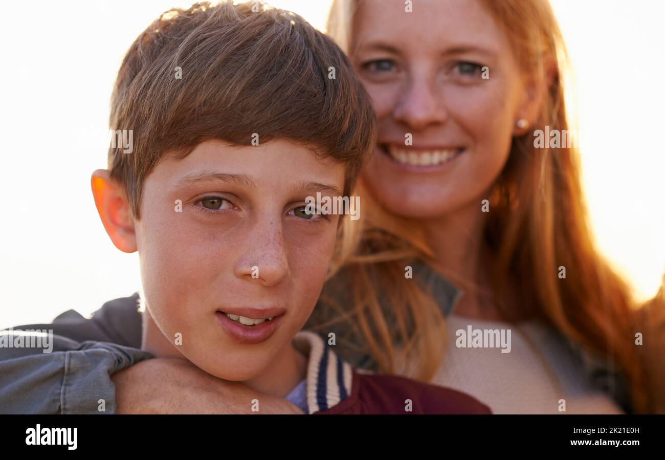 Lei custodisce il suo unico figlio. Ritratto di una madre felice e di un figlio in piedi fuori insieme. Foto Stock