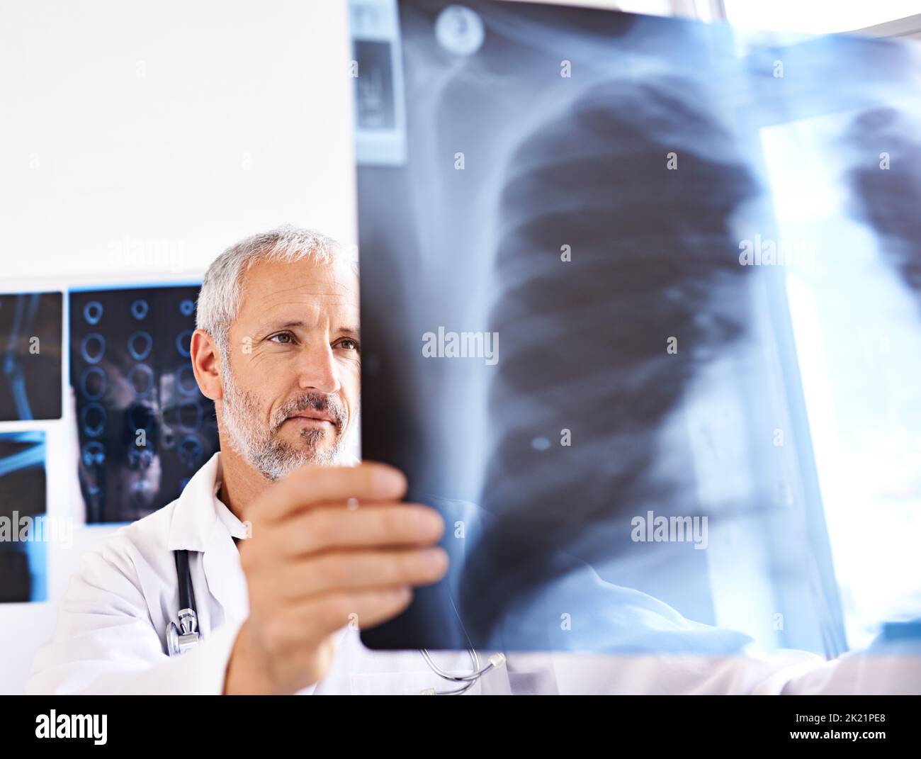 Un medico di sesso maschile maturo che guarda un'immagine radiografica in un ospedale. Foto Stock