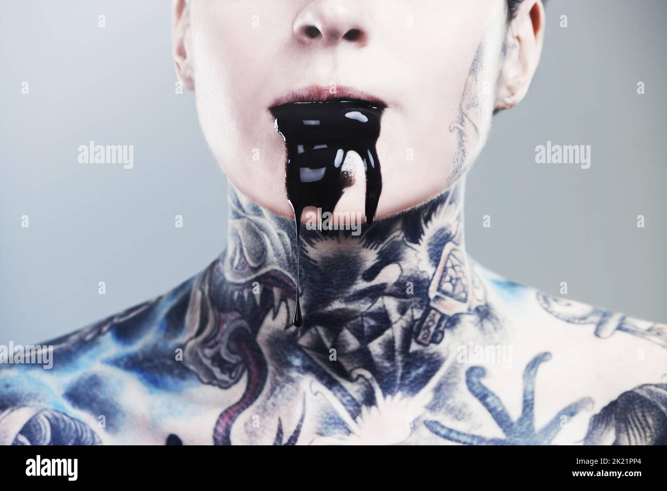 Non è possibile mantenere l'oscurità. Immagine ritagliata di una donna tatuata con inchiostro nero che fuoriesce dalla bocca. Foto Stock