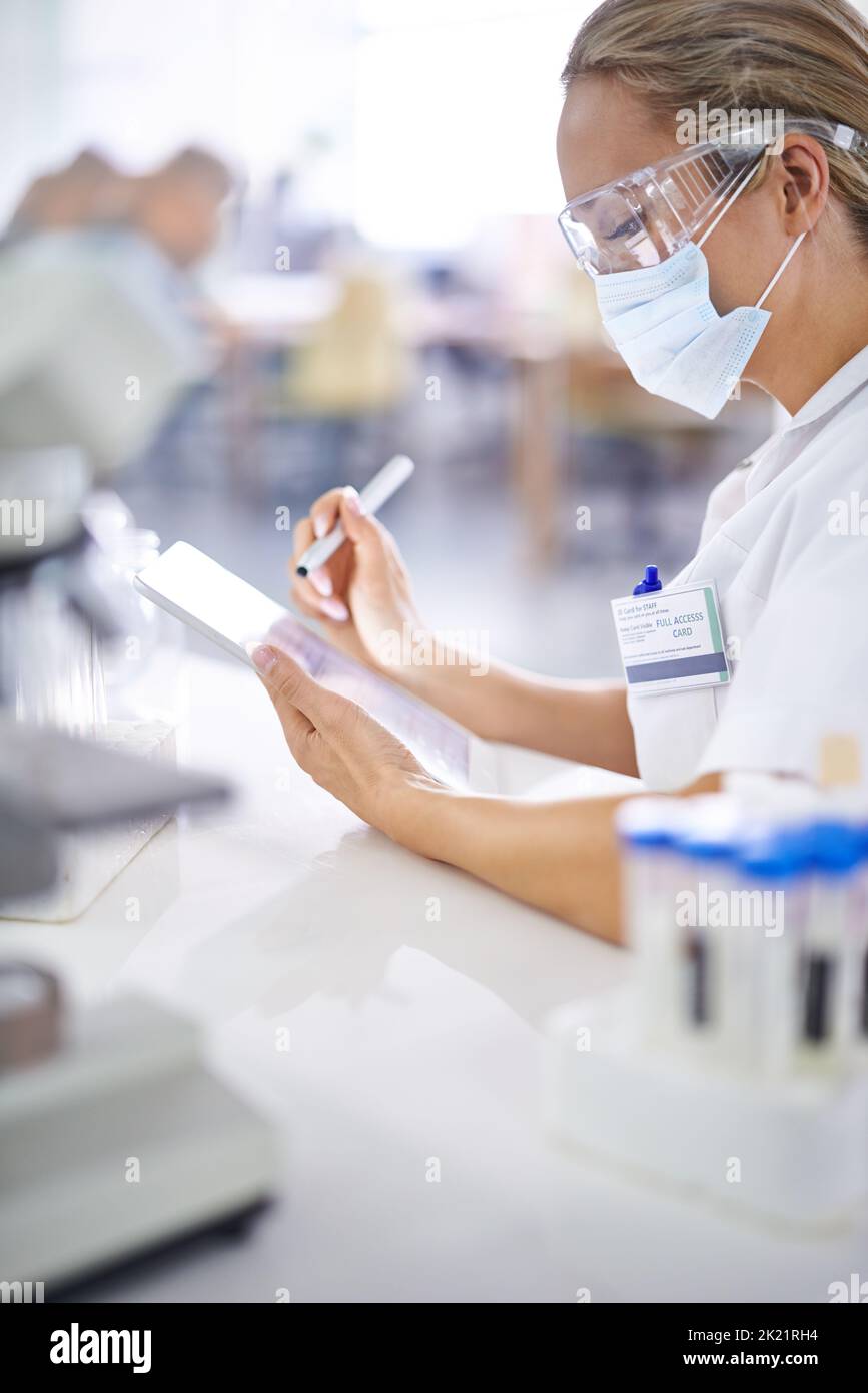 Proprio come pensavo... Un giovane scienziato che registra i suoi risultati in laboratorio. Foto Stock