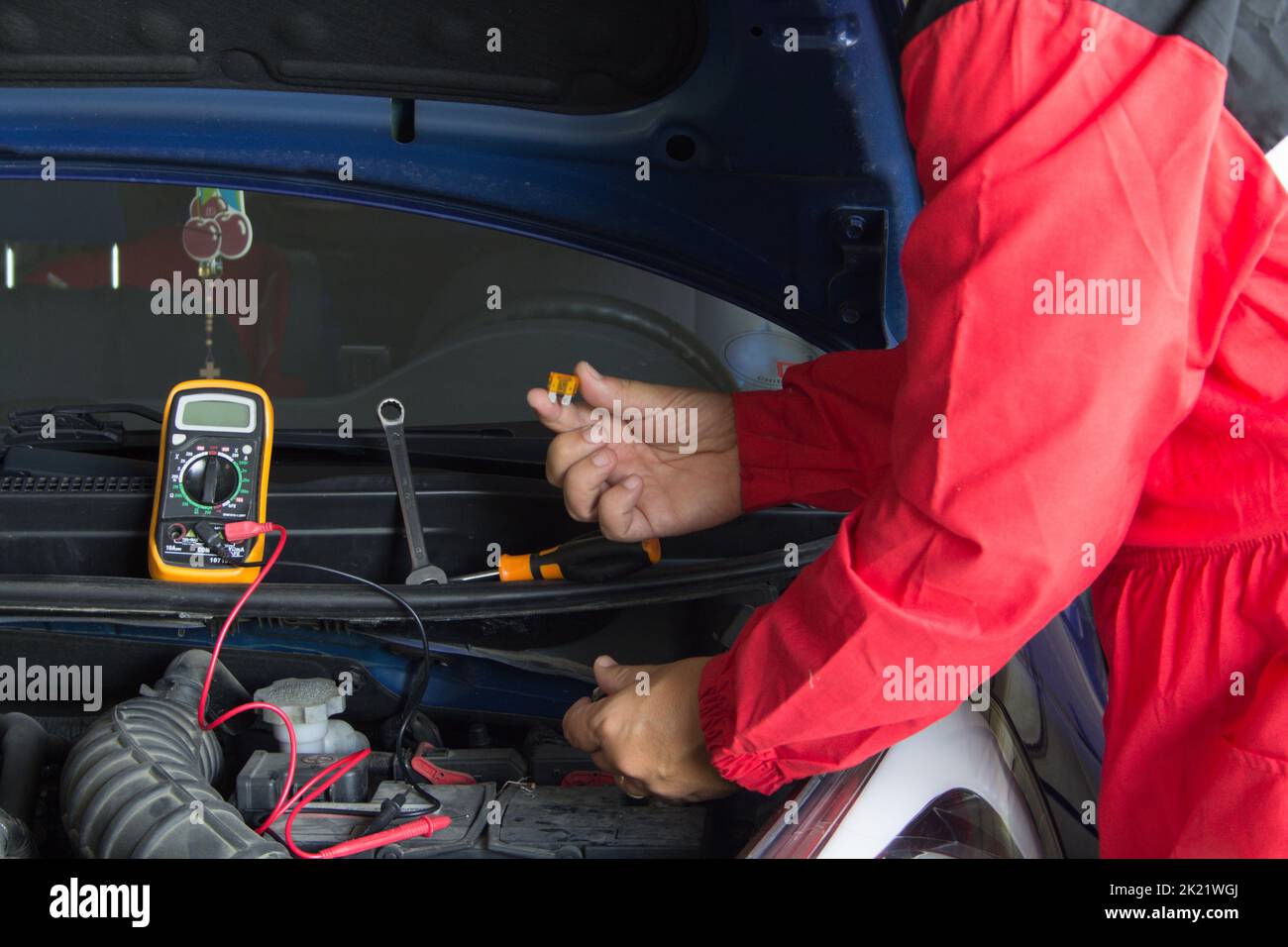 Mani di un elettricista auto che cambia i fusibili su un'auto guasta. Lavori meccanici ed elettronici sulle automobili Foto Stock