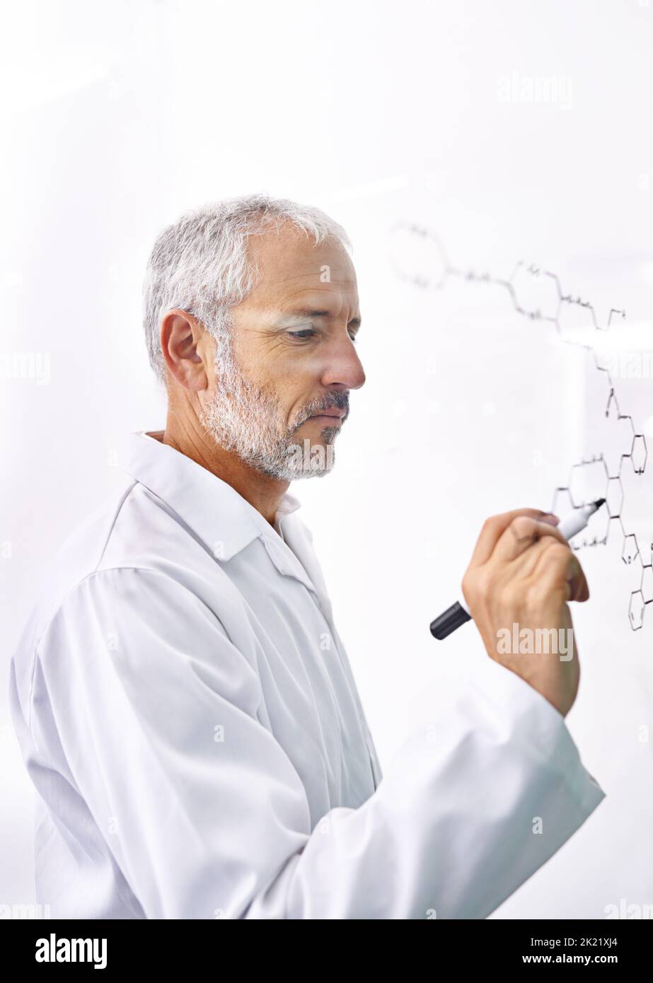 MAD circa le molecole. Uno scienziato maschio maturo che attinge i legami chimici su una superficie di vetro. Foto Stock