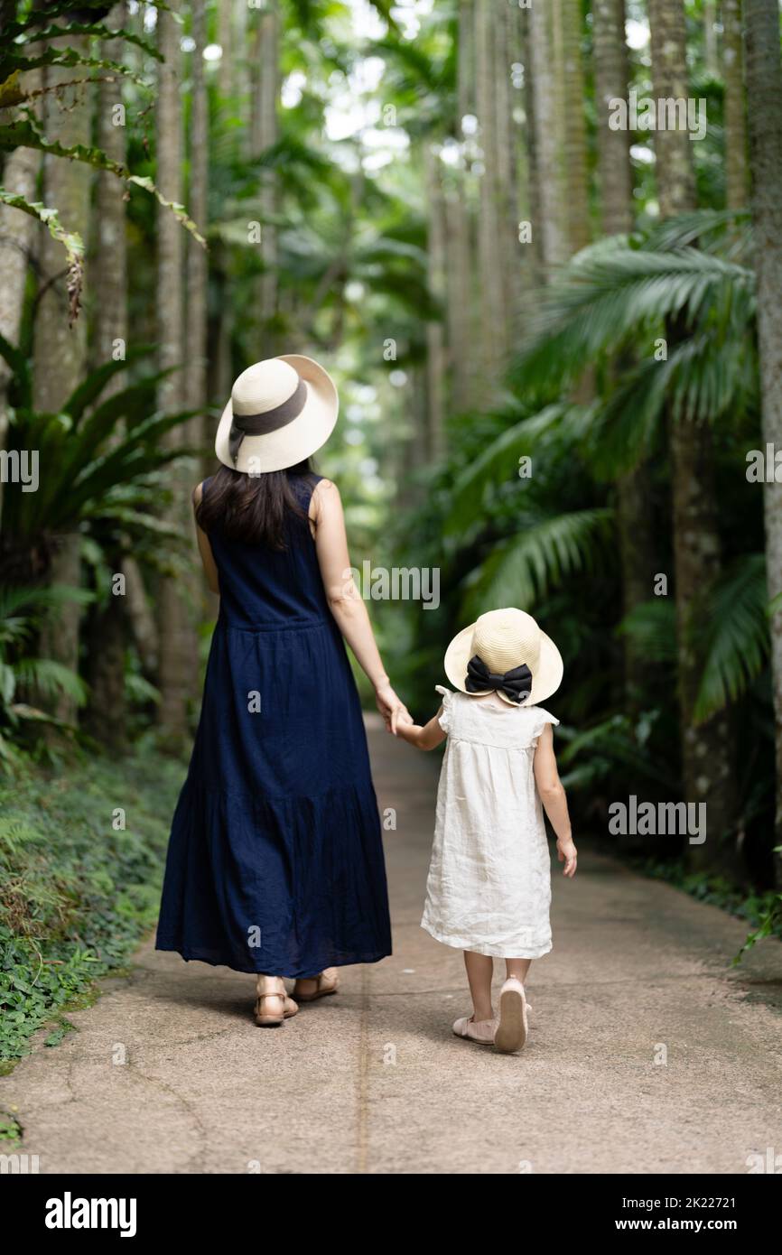Madre e figlia camminano tra le palme tropicali dei Giardini Botanici del Sud-Est di Okinawa, Giappone Foto Stock