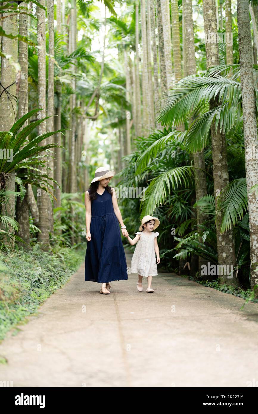 Madre e figlia camminano tra le palme tropicali dei Giardini Botanici del Sud-Est di Okinawa, Giappone Foto Stock