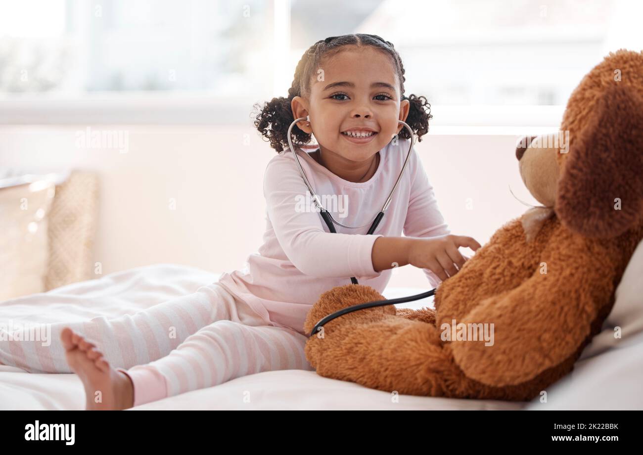 Bambini, stetoscopio e orsacchiotto con una ragazza che gioca medico nella sua camera da letto a casa con un animale farcito. Immaginazione, sanità e medicina Foto Stock