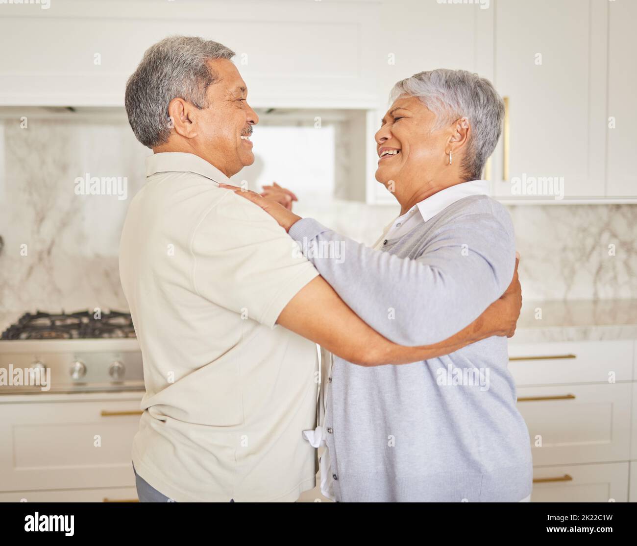 Amore, felice e anziano coppia danza in una cucina a casa, legame e divertimento. Uomo e donna maturi abbracciano, essendo giocosi e amorosi, godendosi loro Foto Stock