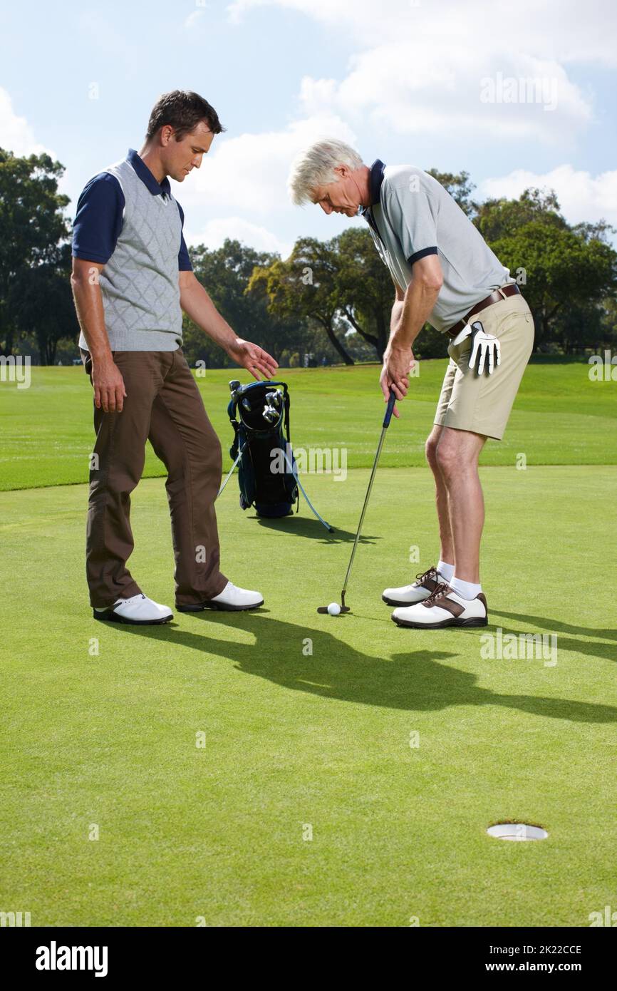 Assicurarsi di tenere il putter correttamente. Due uomini che giocano una partita di golf insieme sul verde. Foto Stock