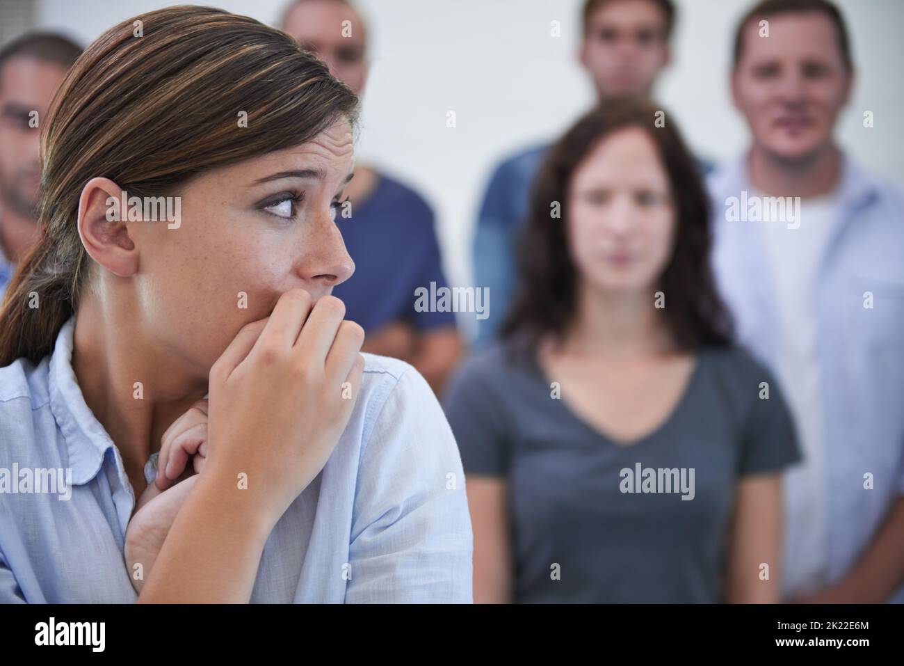 Che cosa devo fare una giovane donna che guarda nervosa davanti ai suoi colleghi. Foto Stock