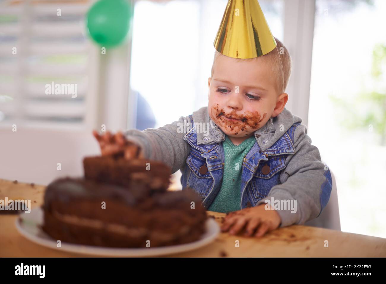 Quella torta non ha mai avuto una possibilità: Un ragazzo che mangiava la torta di compleanno prima della festa. Foto Stock
