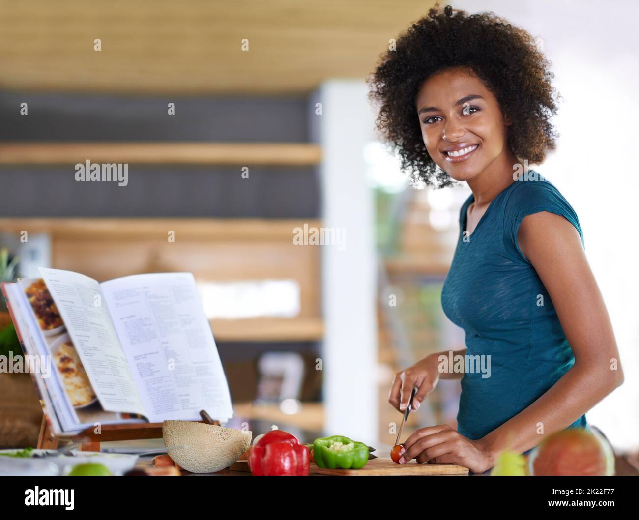 Creare un piatto delizioso da verdure sane. Una giovane donna che cucina da un ricettario. Foto Stock