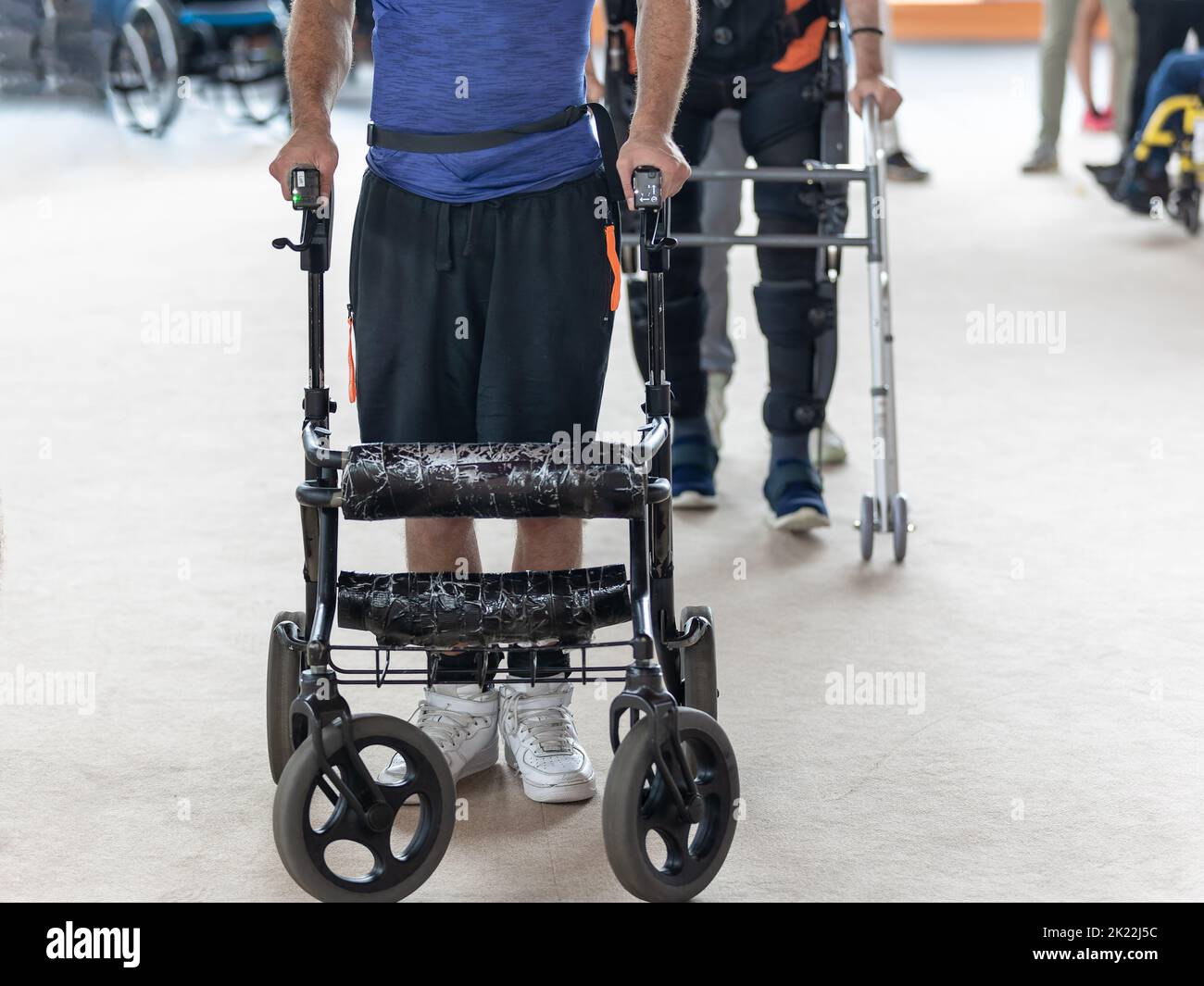 Ragazzo con ridotta capacità motoria che si muove in posizione eretta con il supporto dei carrelli Walker. Foto Stock