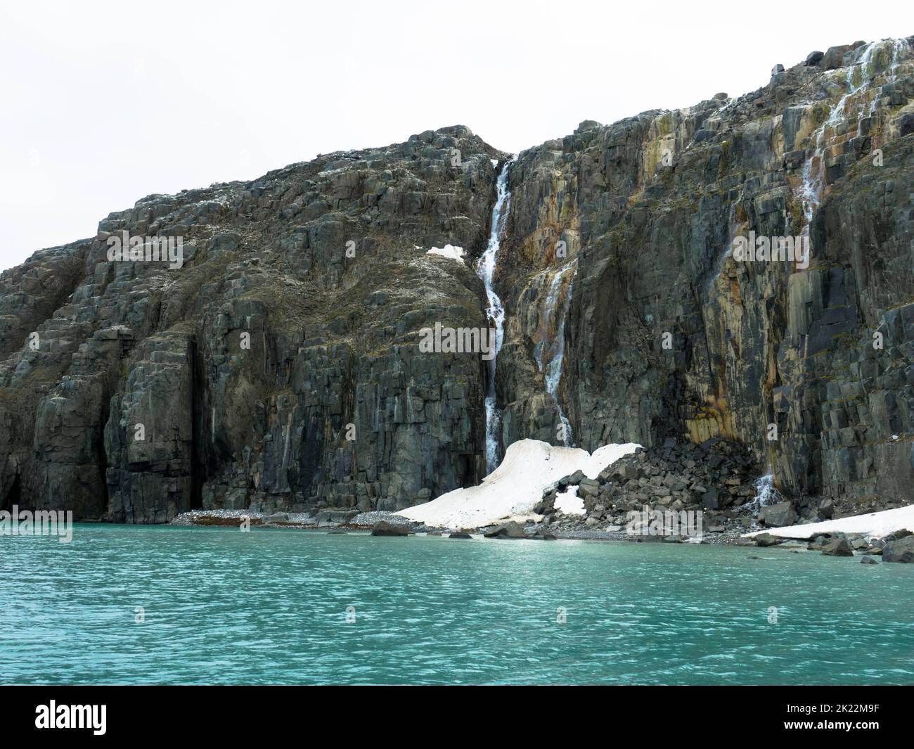 Vista spettacolare di una cascata presso un ghiacciaio. La scogliera degli uccelli di Alkefjellet è la scogliera più famosa dell'arcipelago di Spitsbergen. Hinlopen Fjord, Svalbard. Foto Stock