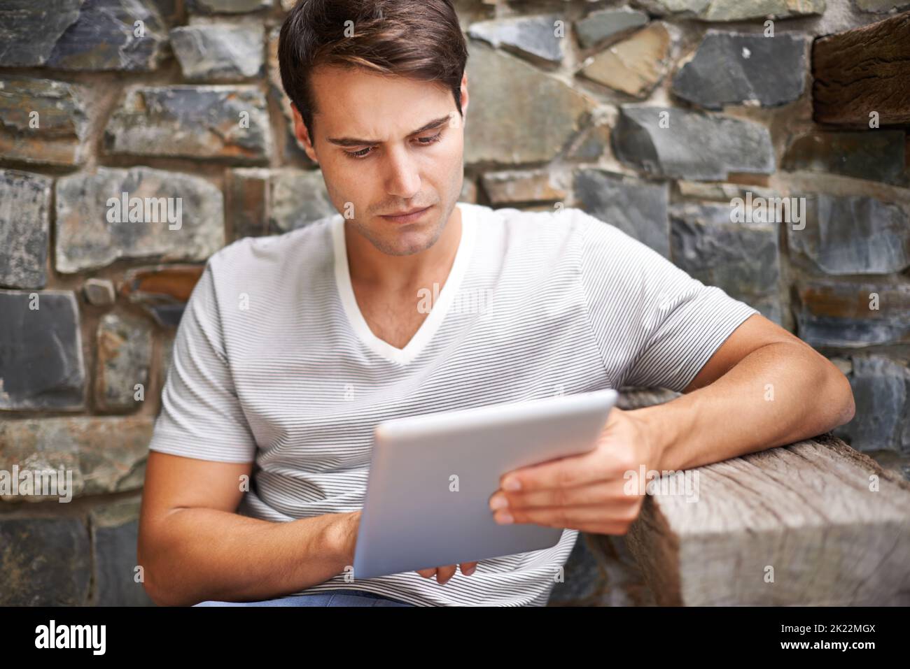 La prima cosa da mettere in valigia quando si va in vacanza: Un bel giovane uomo che usa il suo tablet digitale all'aperto. Foto Stock