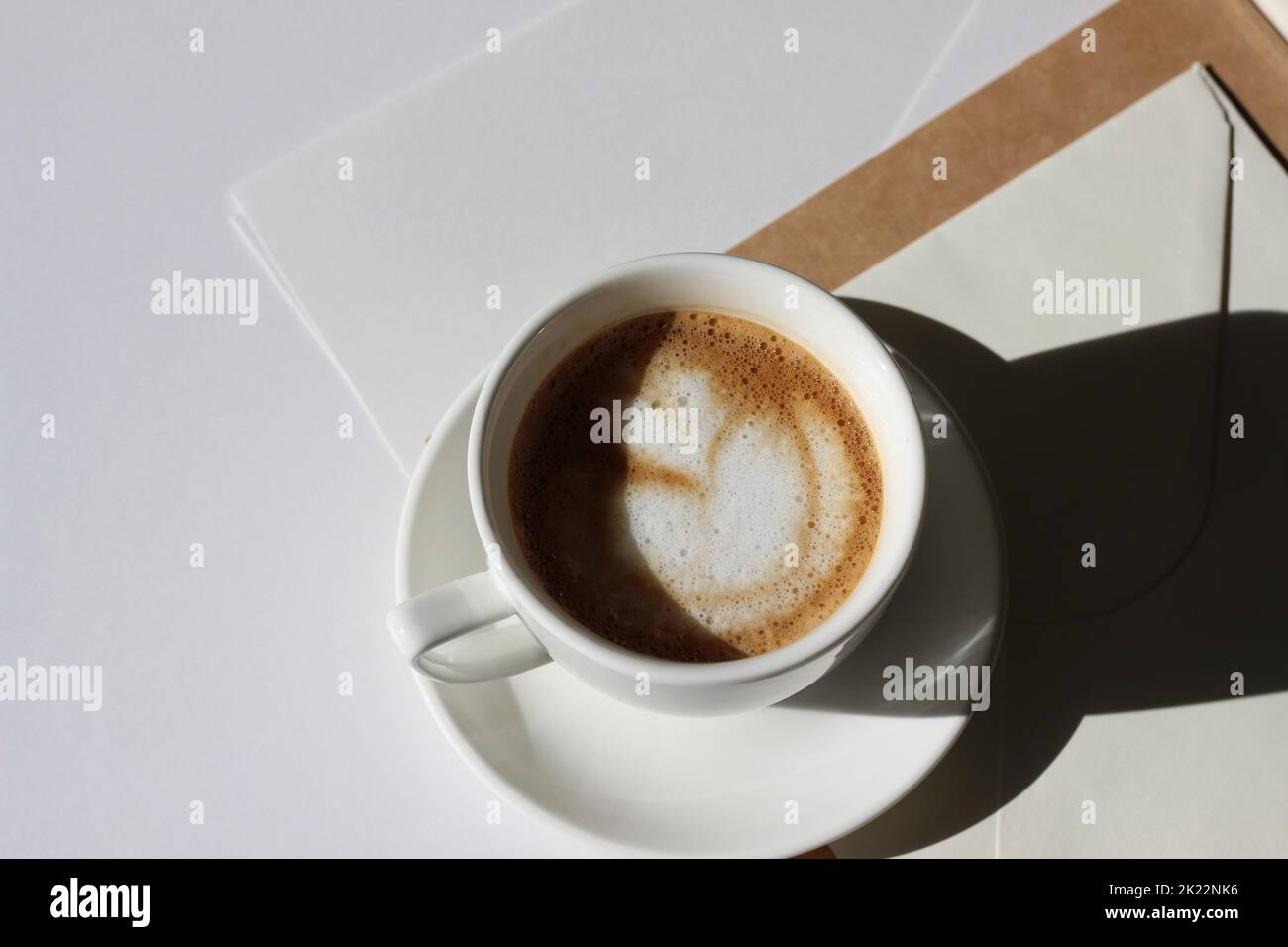 Piatto da scrivania minimal con caffè fresco e buste su sfondo bianco. Pausa caffè Business Meeting. Foto Stock