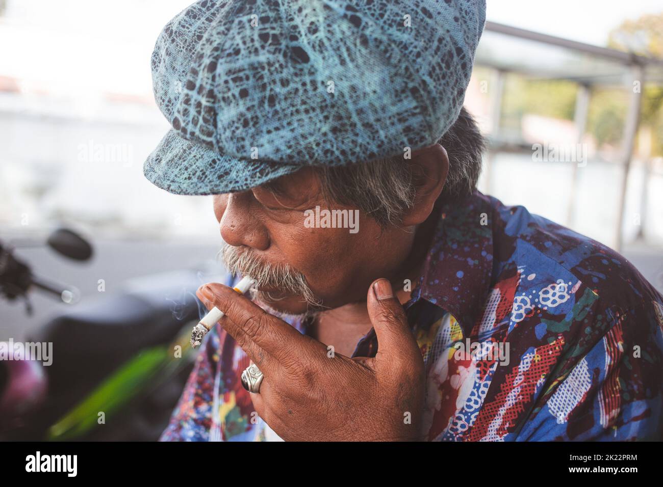 Un vecchio con un cappello classico e una sigaretta fumante a Yogyakarta, Indonesia Foto Stock